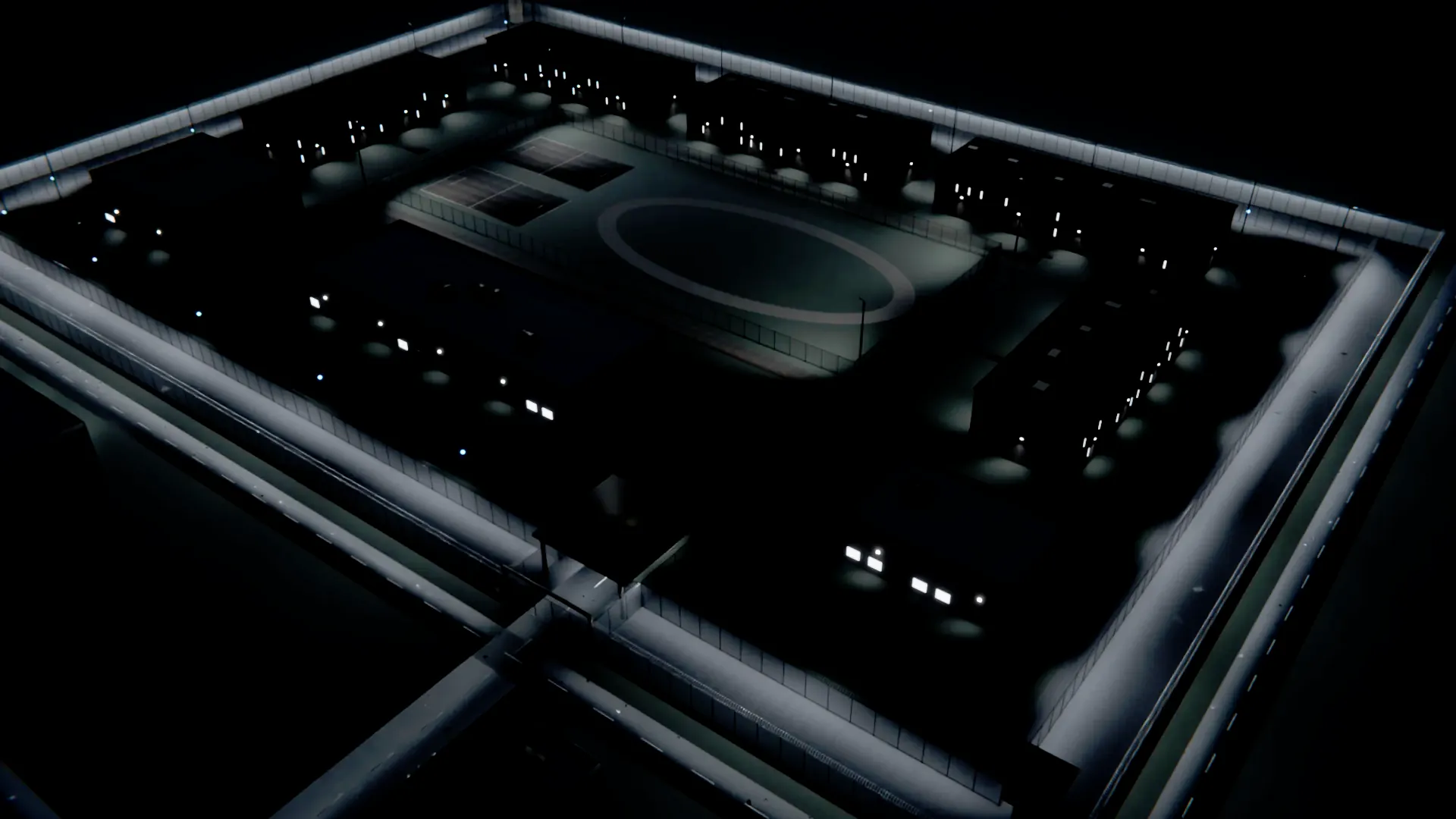 A corrections facility at night, seen from above: a floodlit double fence with razor wire around low housing units and a yard, with sensors on some of the perimeter light poles.